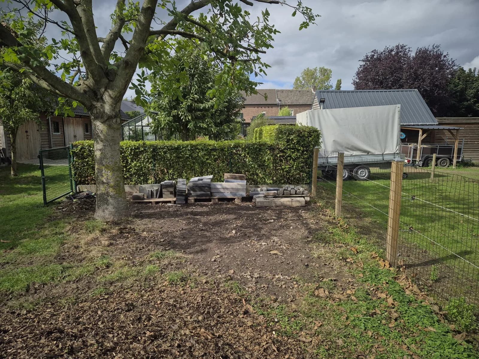 Zelfde tuinhoek opgeruimd, bruikbare tegels netjes gestapeld na het afvoeren van het puin