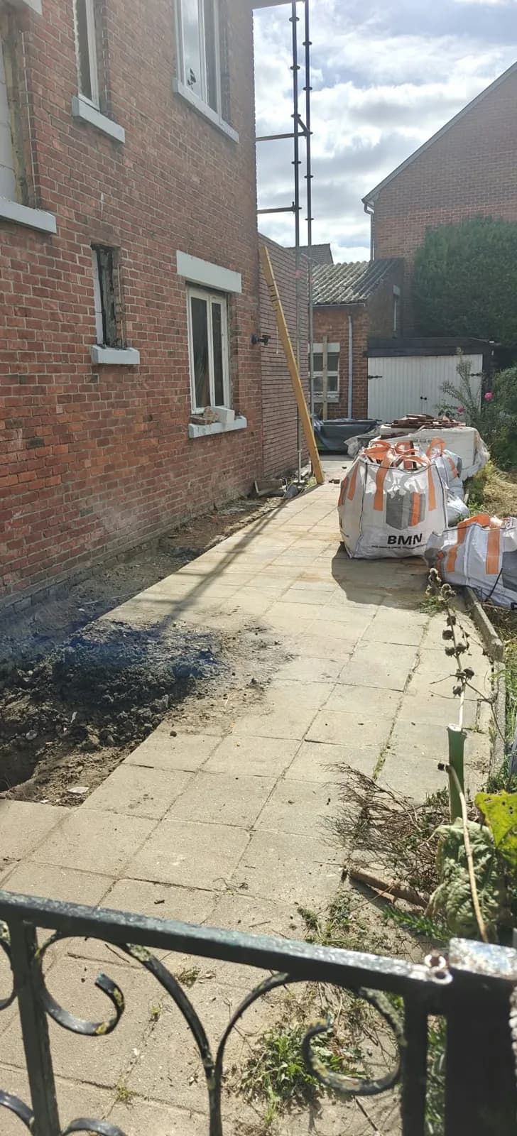 Hetzelfde tuinpad vrijgemaakt na het afvoeren van het sloopafval, enkel de big bags van de dakwerker blijven staan