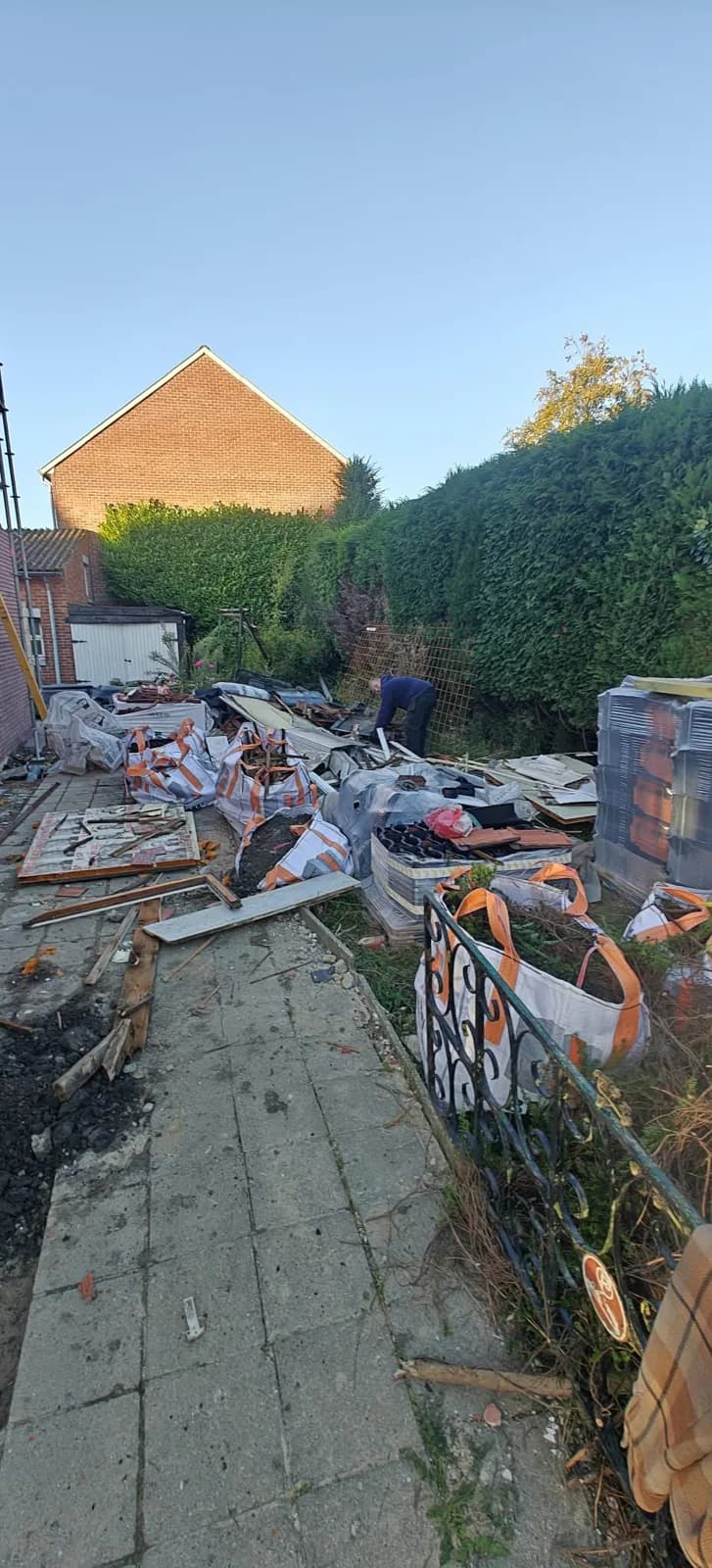 Tuinpad vol gebroken dakpannen, planken en sloopafval voor de opruiming door BR-ontruimingen in Limburg